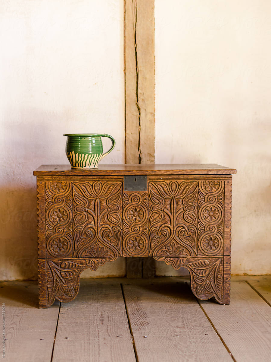Old green pottery sitting on an ornate historic wooden chest