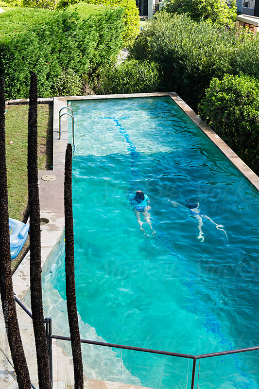 two teen girls swimming in a large backyard pool