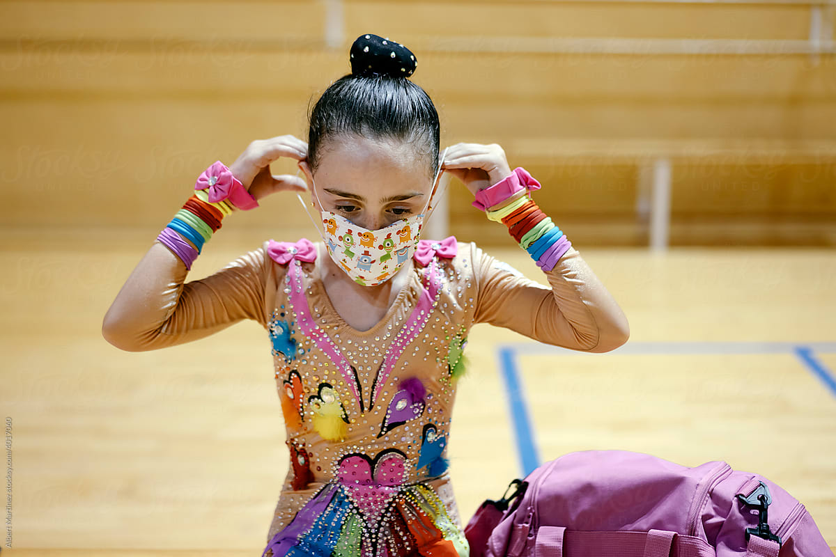 Gymnastic young girl putting on a face mask in training