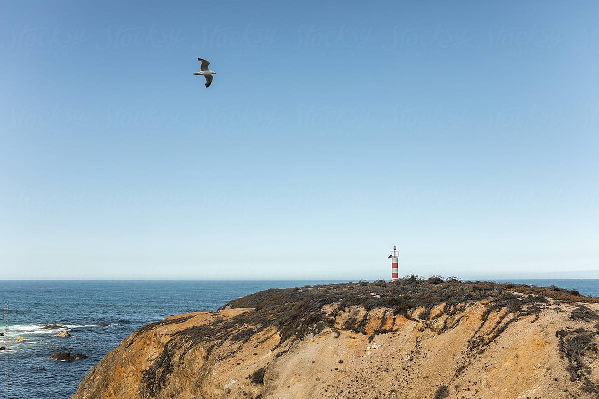 landscape of a beach with a lighthouse on top of a cliff