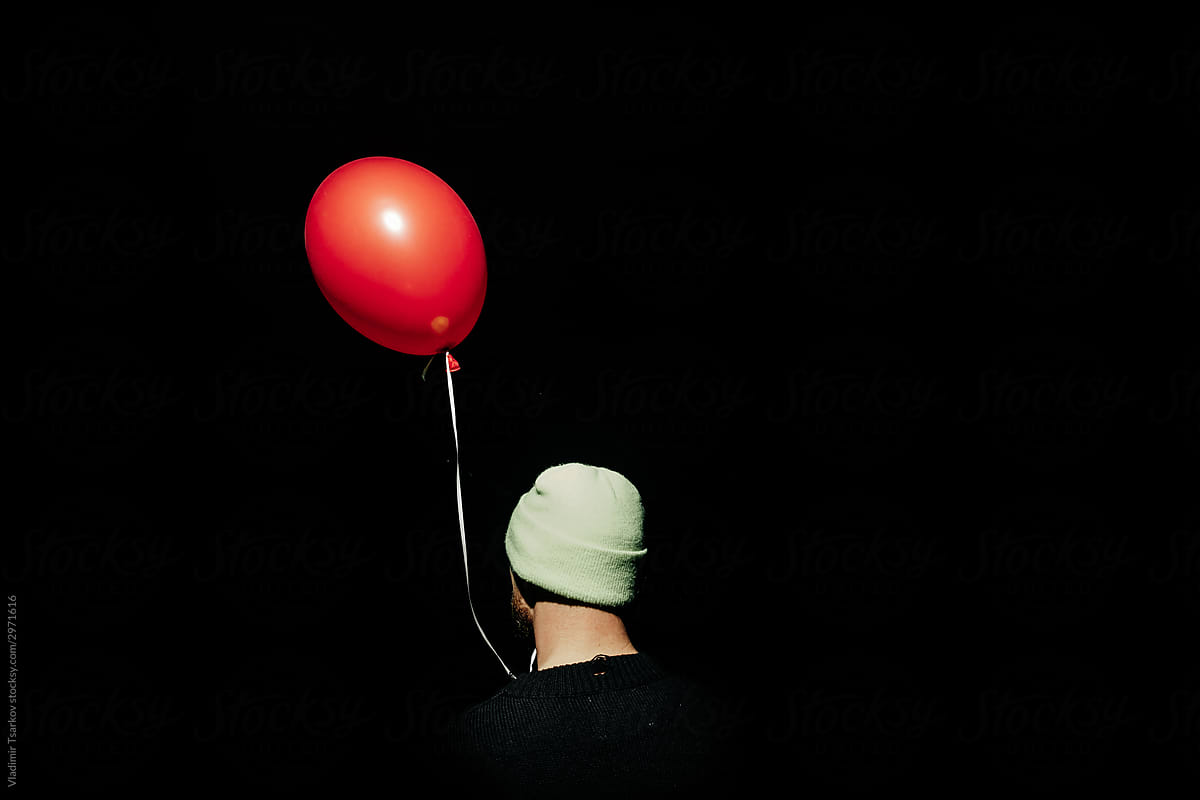 lonely anonymous person with red balloon in the dark