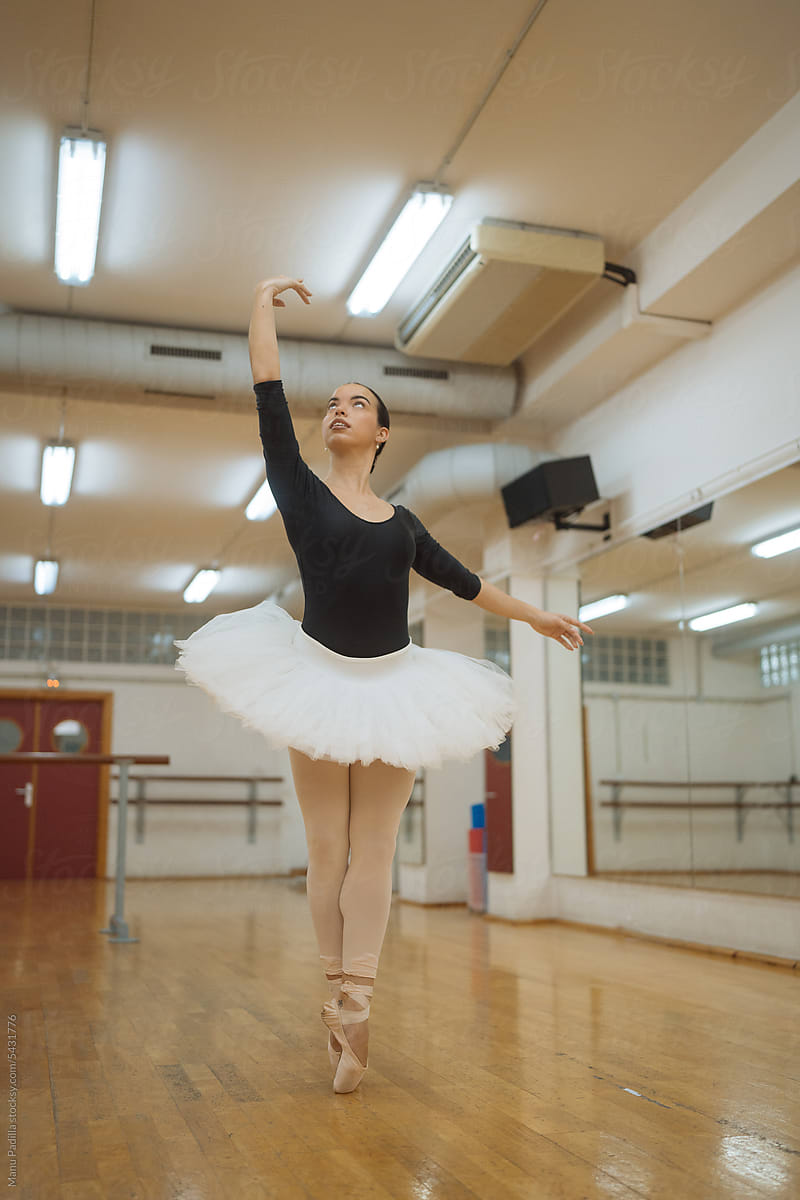 Fit young ballerina performing ballet pose in studio