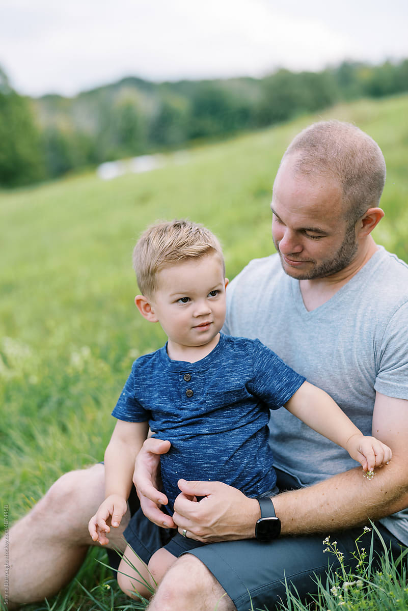smiling father and son in grass together