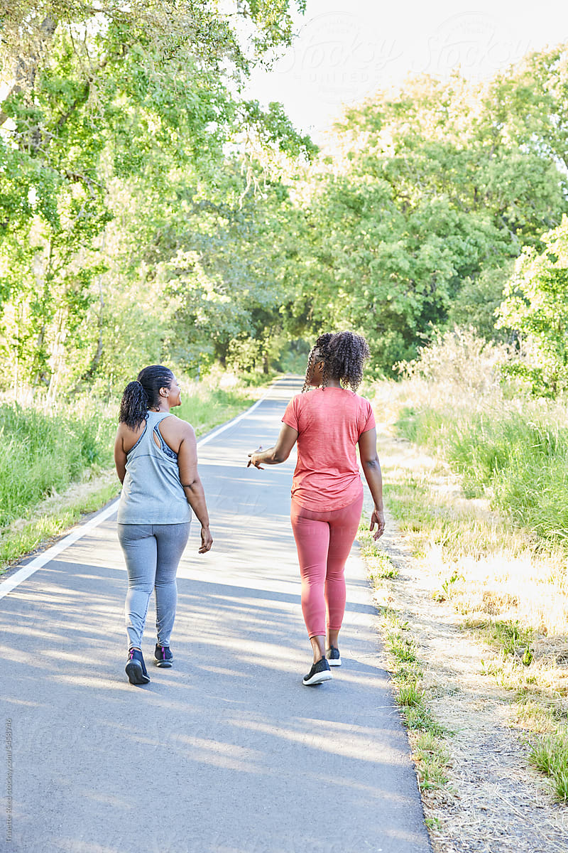 Black girlfriends walking and exercising on a trail together in nature