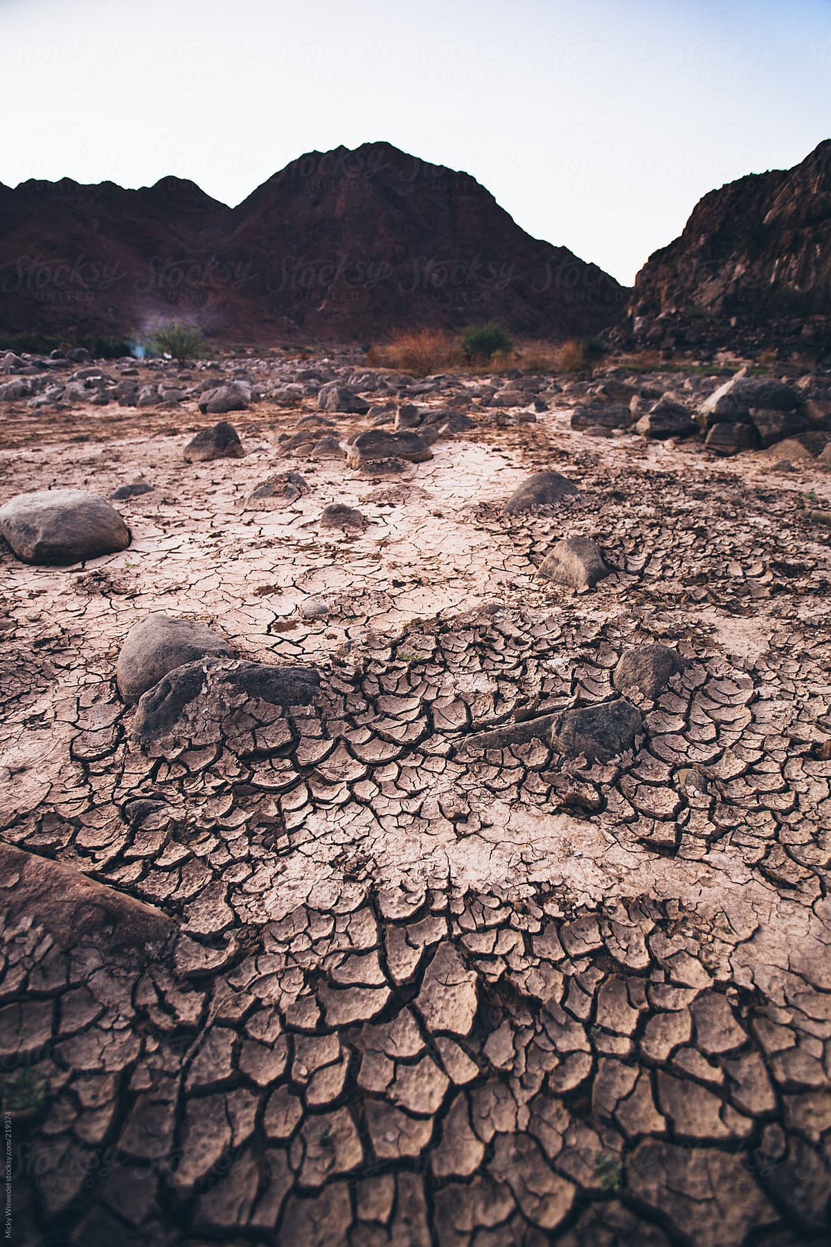 cracked mud and boulders in a dried out river bed