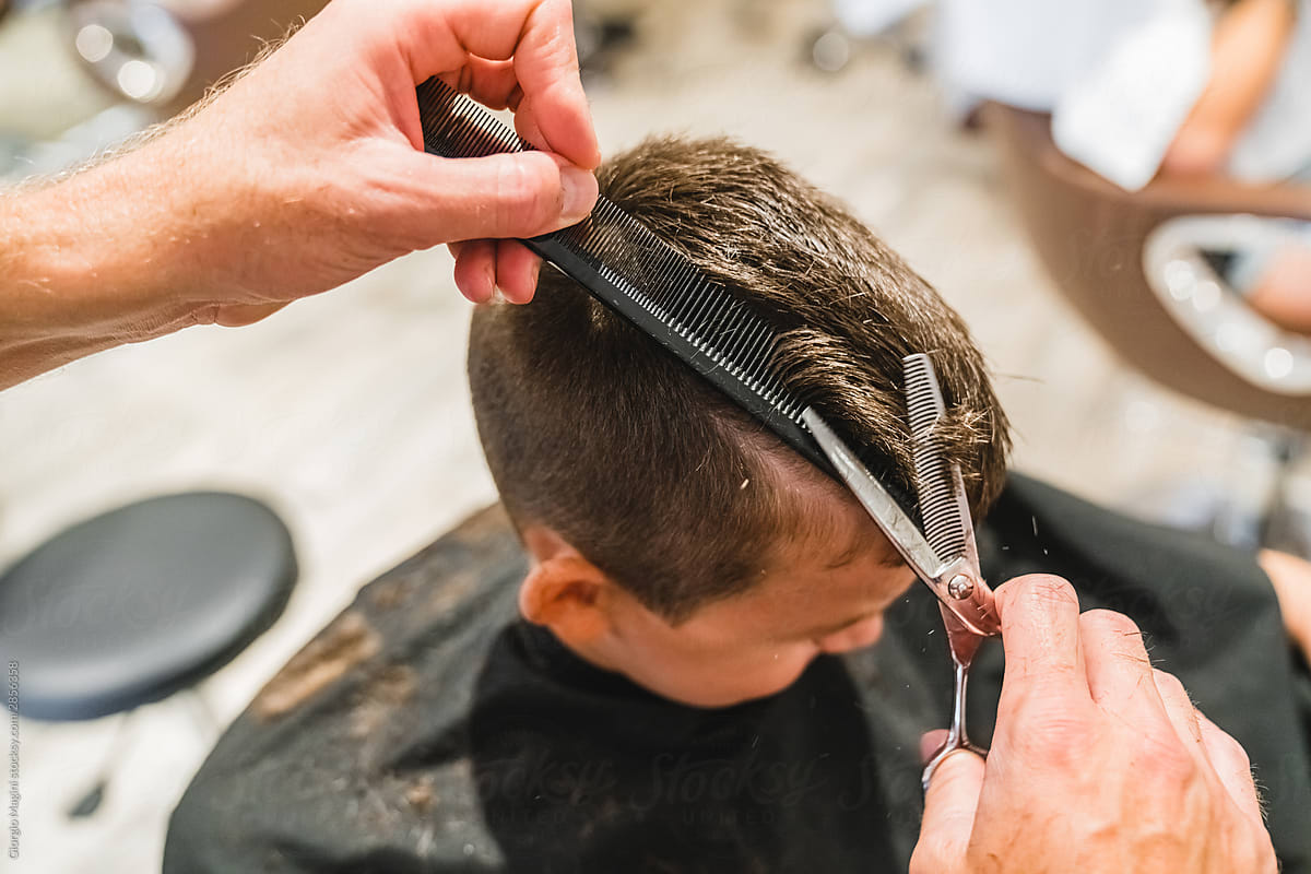 Crop barber cutting hair of boy