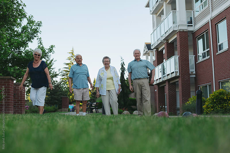 Group of happy, healthy caucasian seniors playing fun game of bocce ball outside