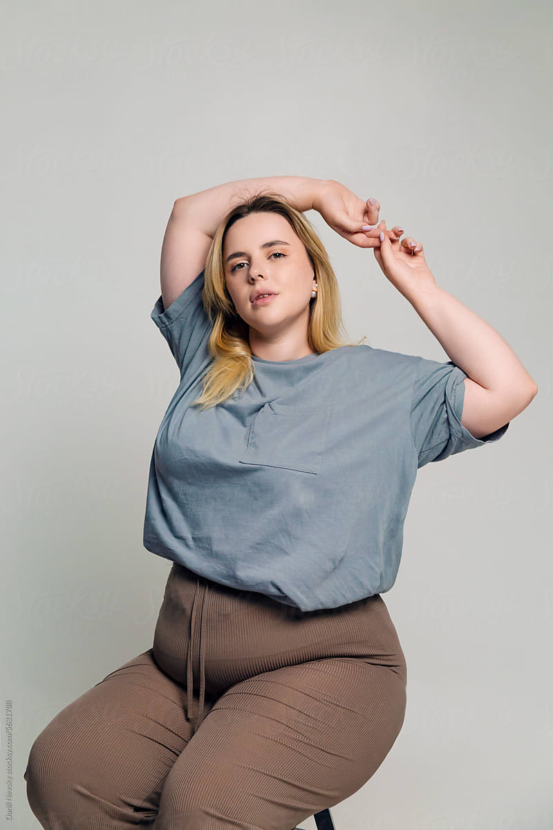 Young plus size woman sitting on stool with hands