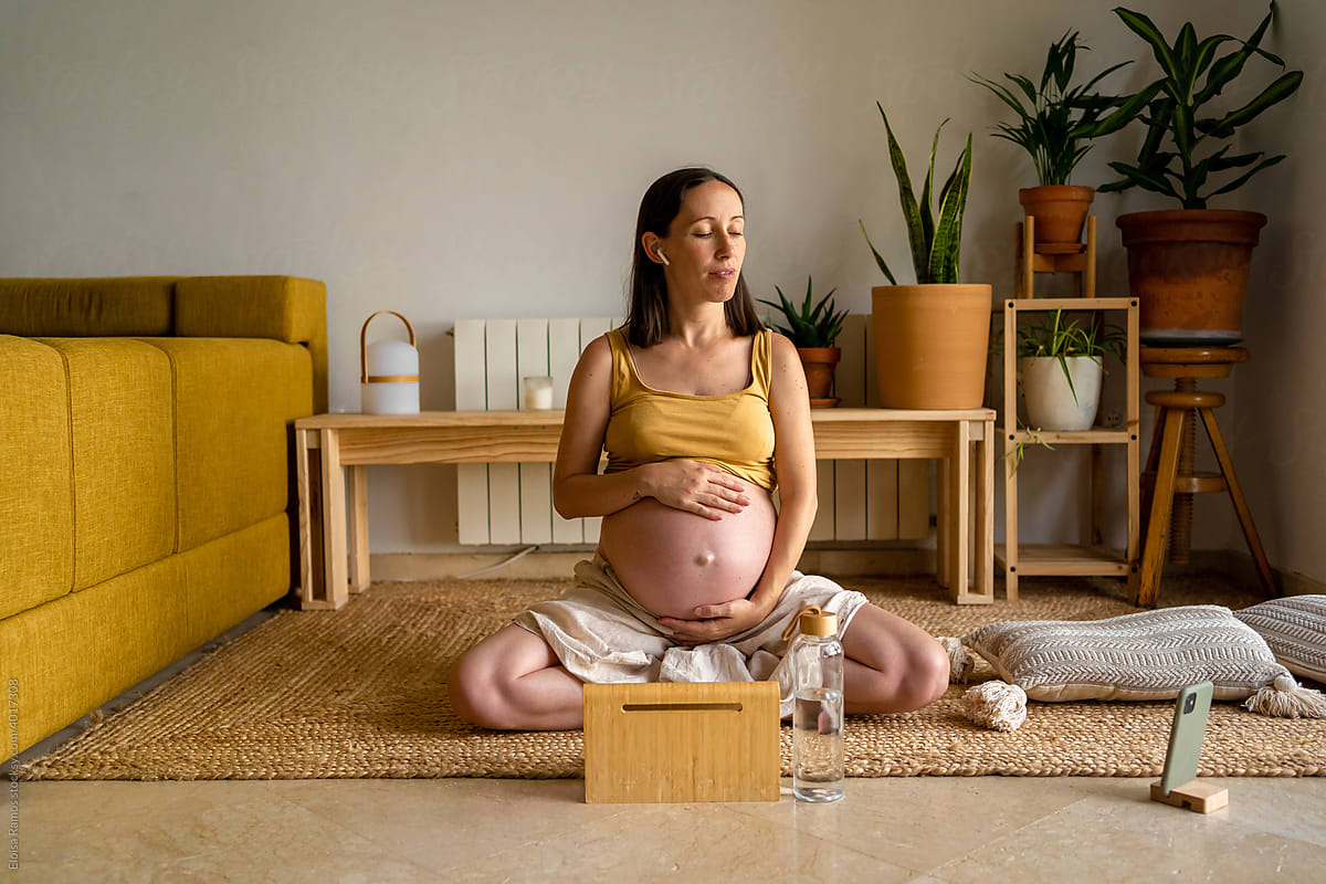 Gravid woman doing meditation on te floor at home