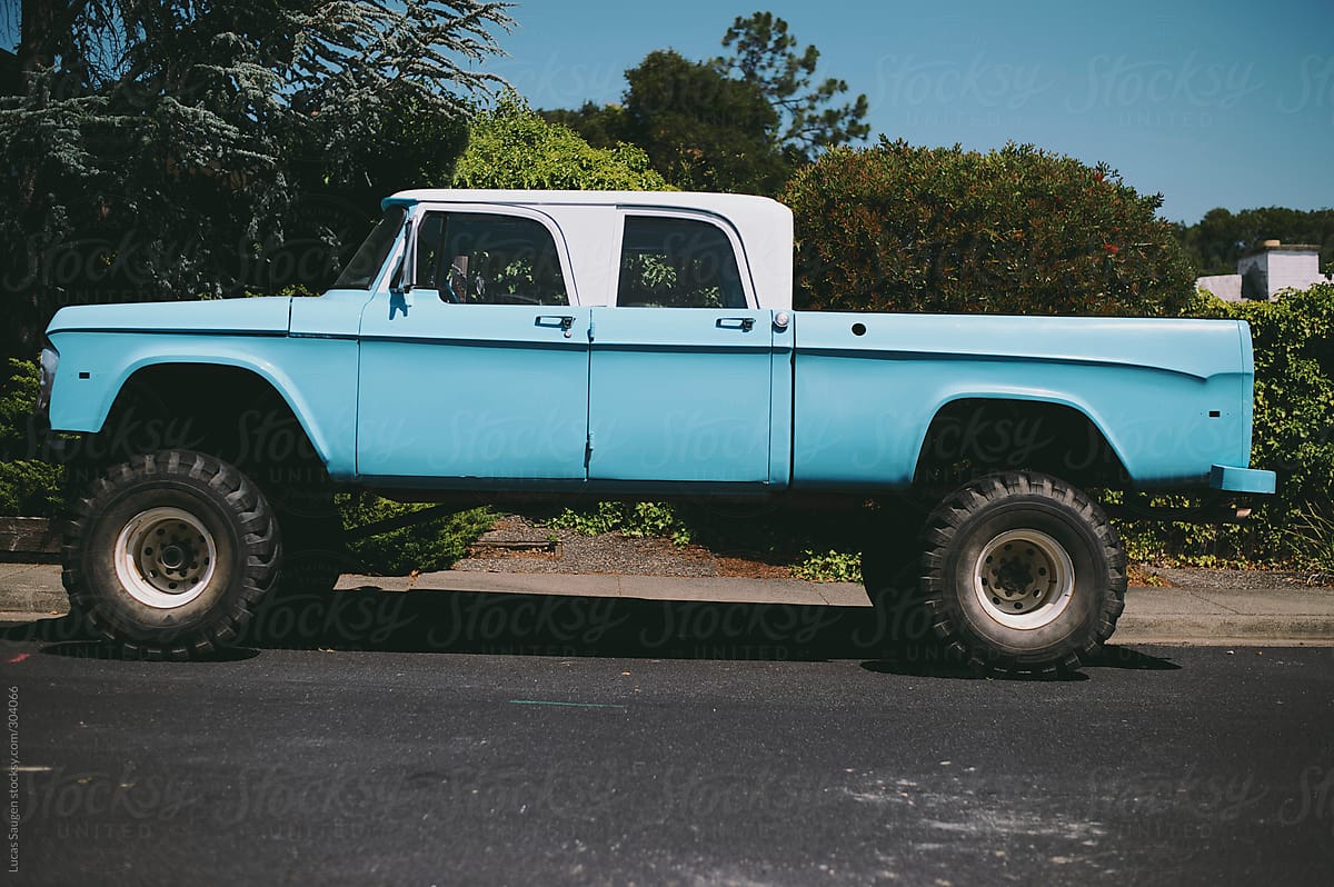 Vintage blue mud truck sits on a rural street
