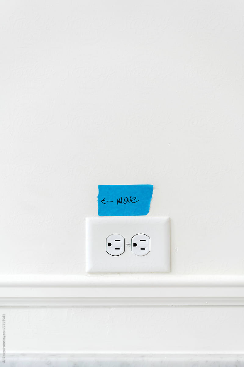 Outlet with painter\'s tape on white wall