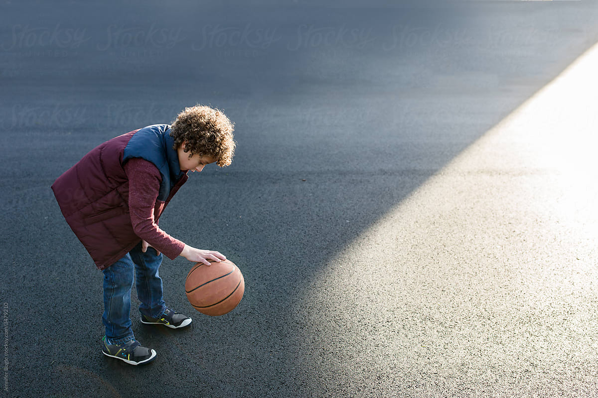Boy bouncing basketball on blacktop