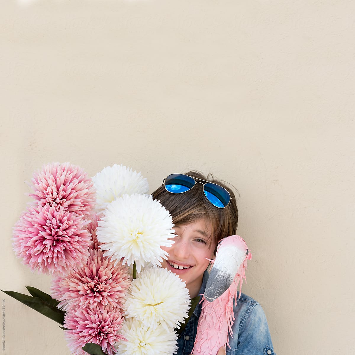 Boy smiling at camera, while holding many flowers