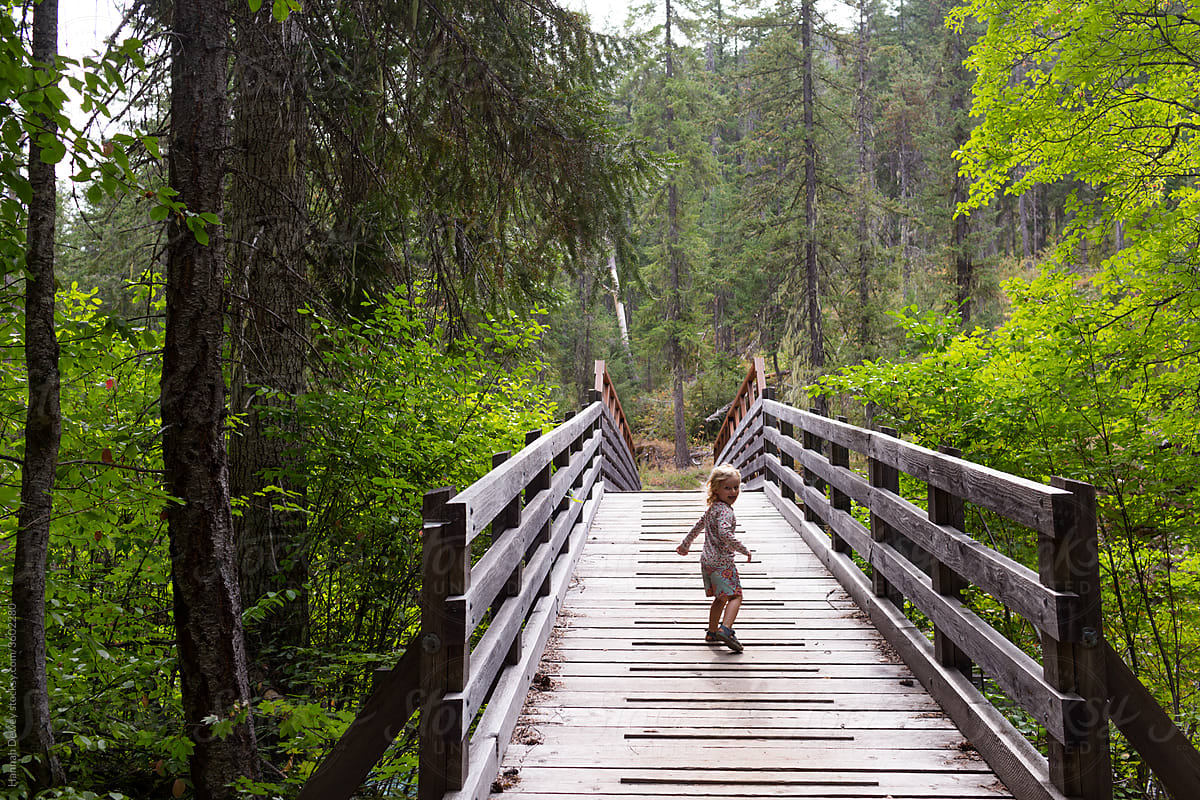 Little girl runs across a bridge on a hike