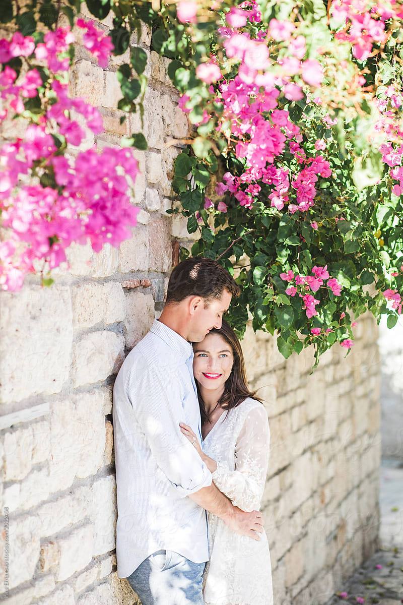 Couple in love standing under beautiful blooming fuchsia flower tree