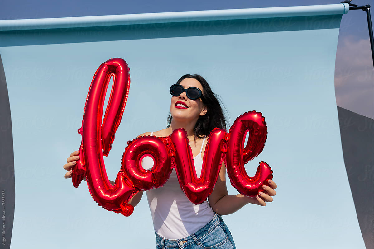 Radiant woman holding balloon with the word love