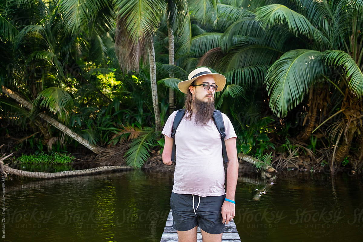 A male with a hat is standing on the bridge in Seychelles.