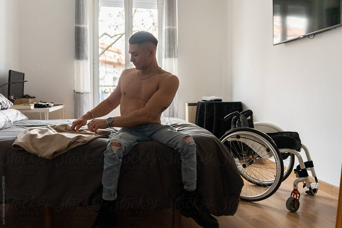 Young Man With Disability Takes Off His Shirt In His Room.