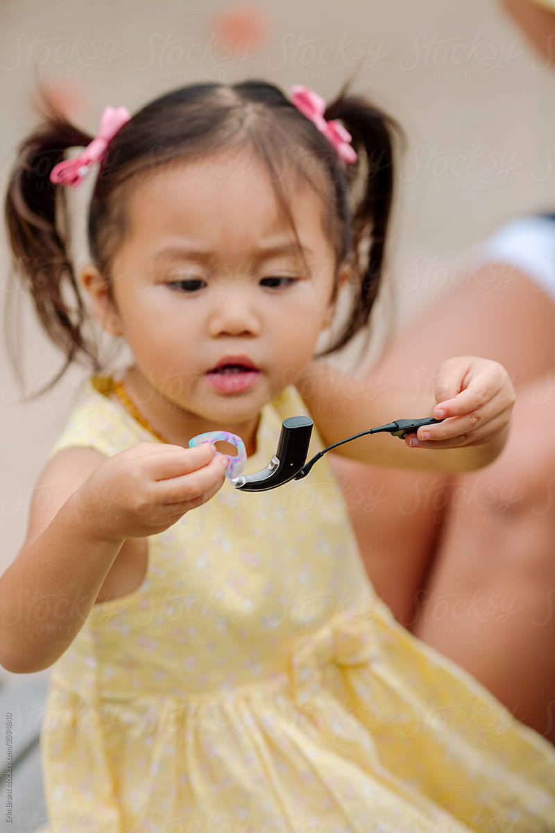 Young Asian girl looking at cochlear implant