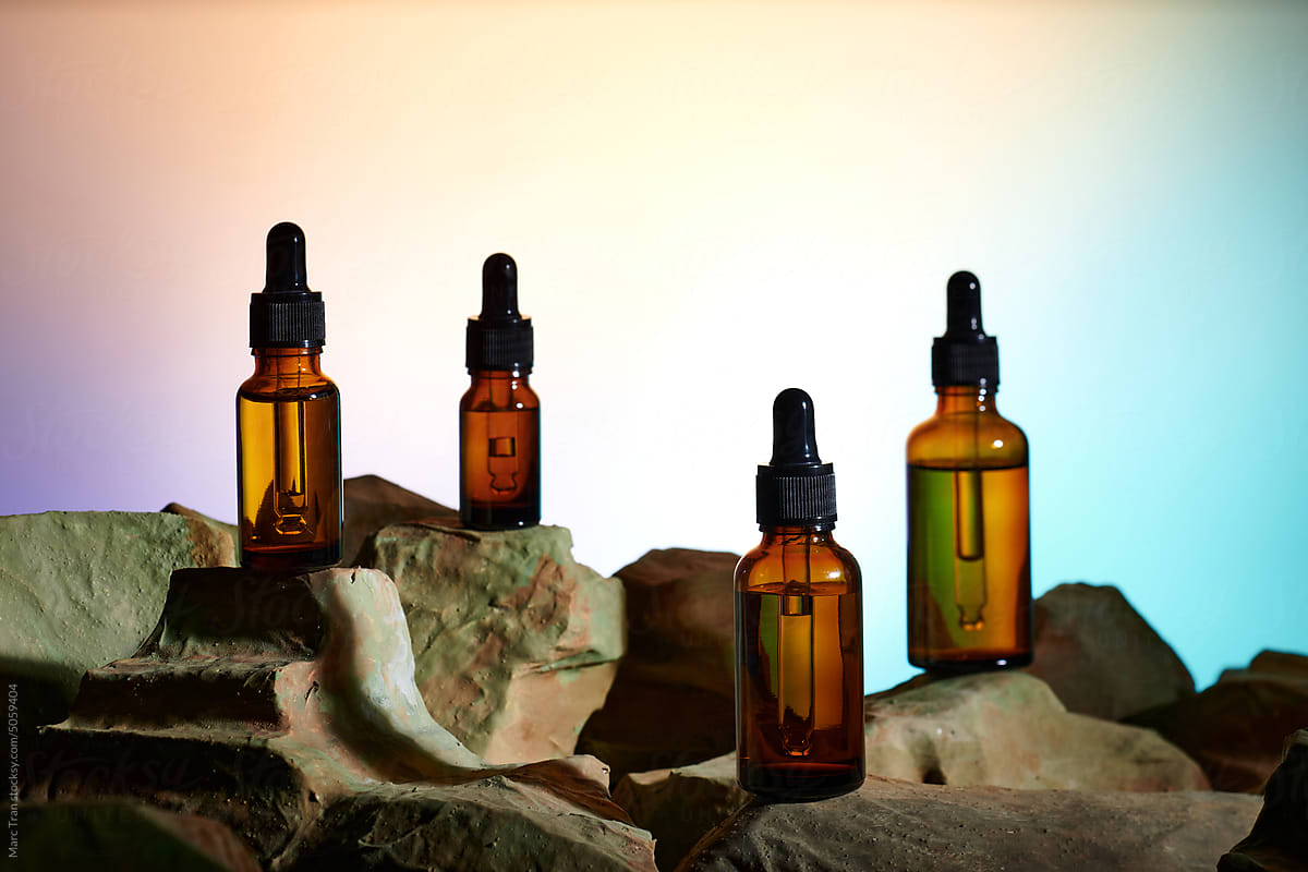 cosmetic bottles with droppers on stone on white background