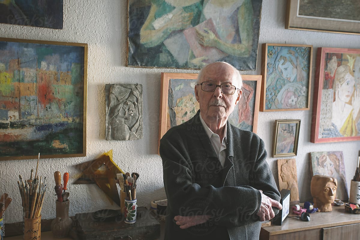 Portrait of old man standing on his studio of painting and sculpture.
