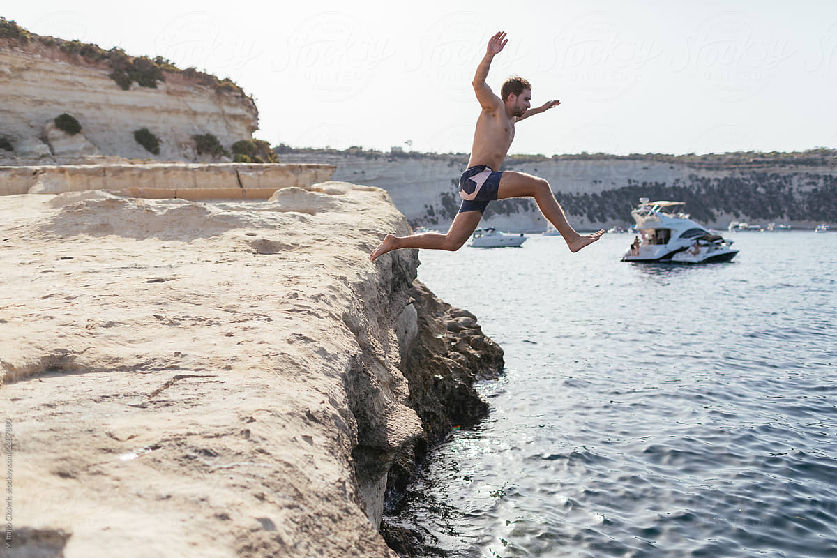 Man jumping from a rock in the sea