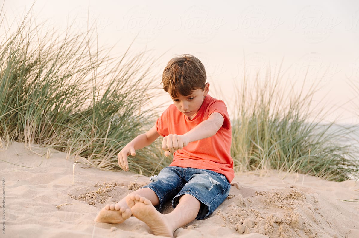 Child having fun playing with sand at the beach