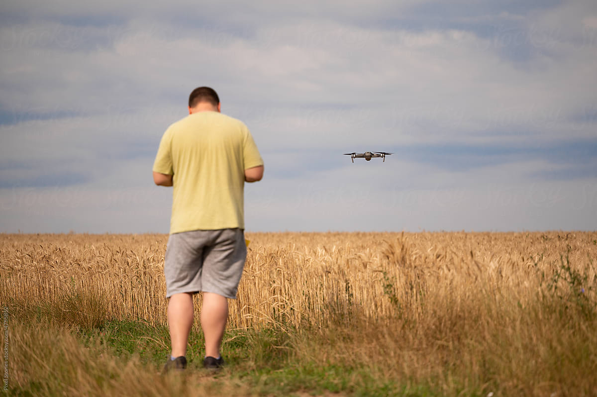 Anonymous man using drone to shoot wheat field