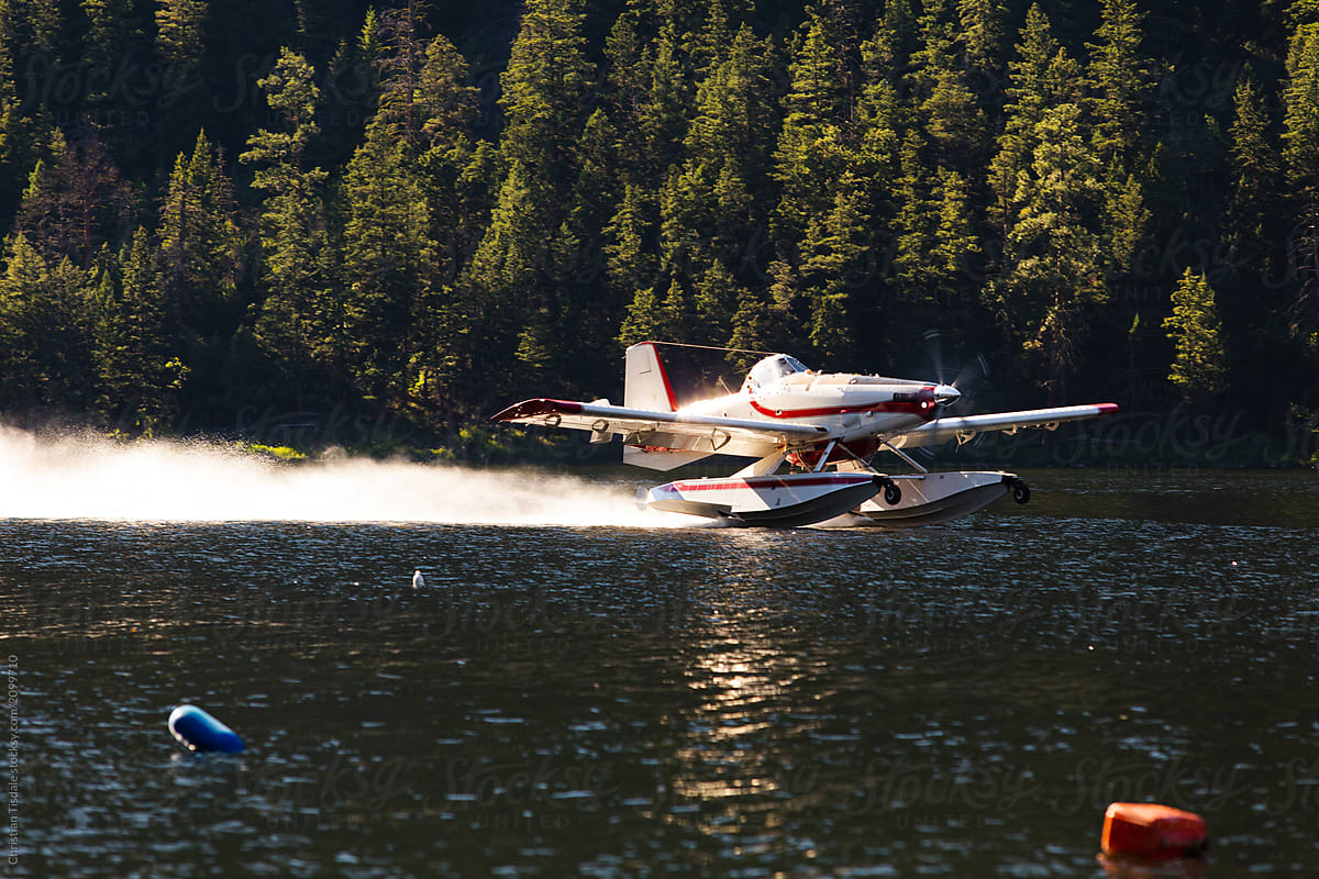 A forest fire fighting floatplane taking off from a lake after filling it\'s tanks