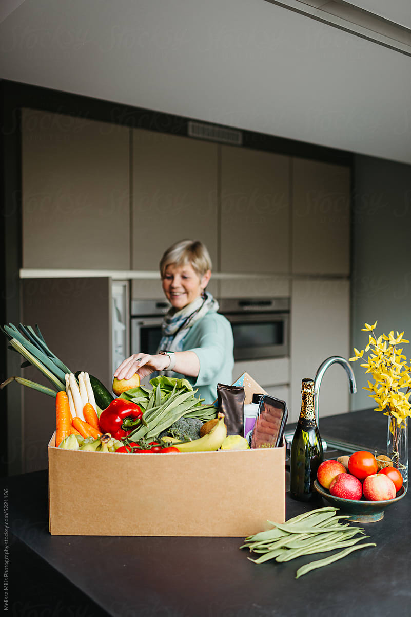 Candid moment of older woman unpacking groceries at home