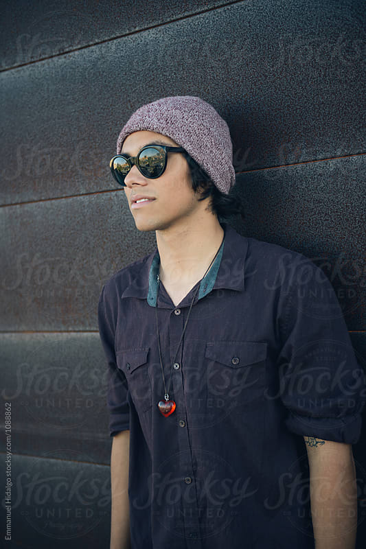 Young trendy male leaning against a rusted wall