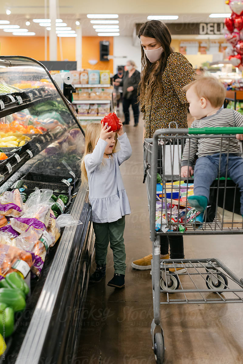 A Child Picks a Bell Pepper at a Grocery Store