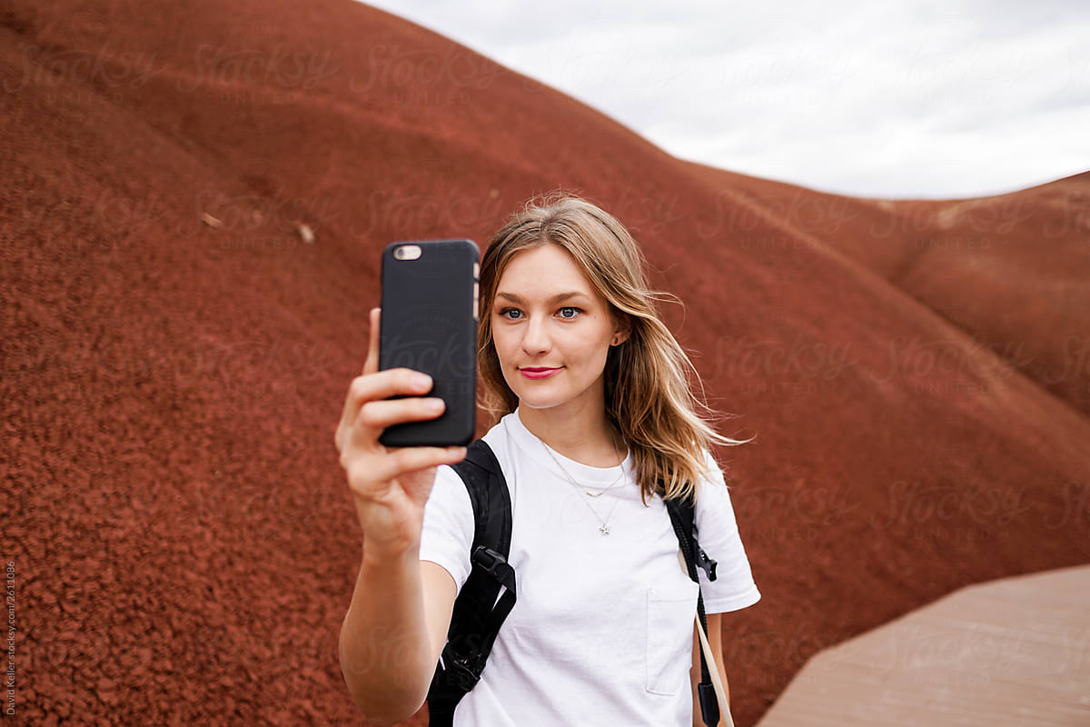 Woman taking a selfie on a boardwalk in scenic red hills