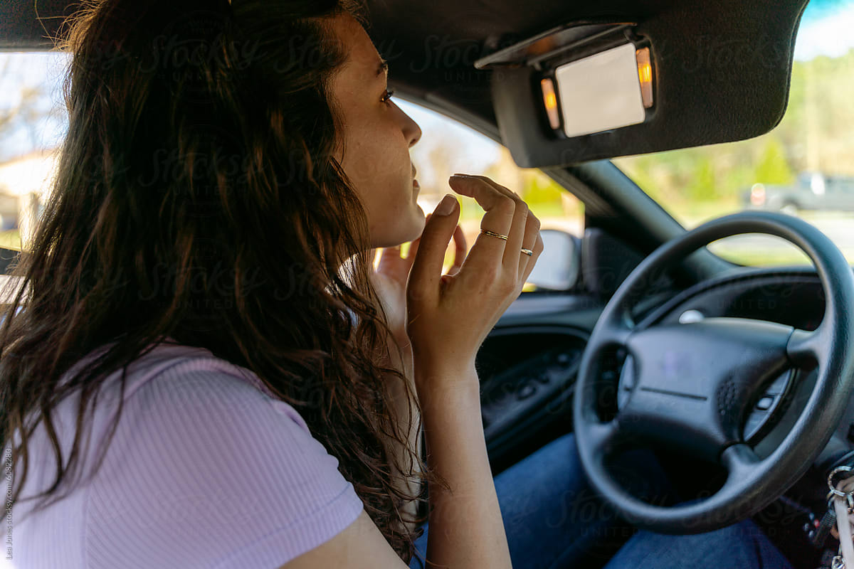 young woman fixing her make up in the car