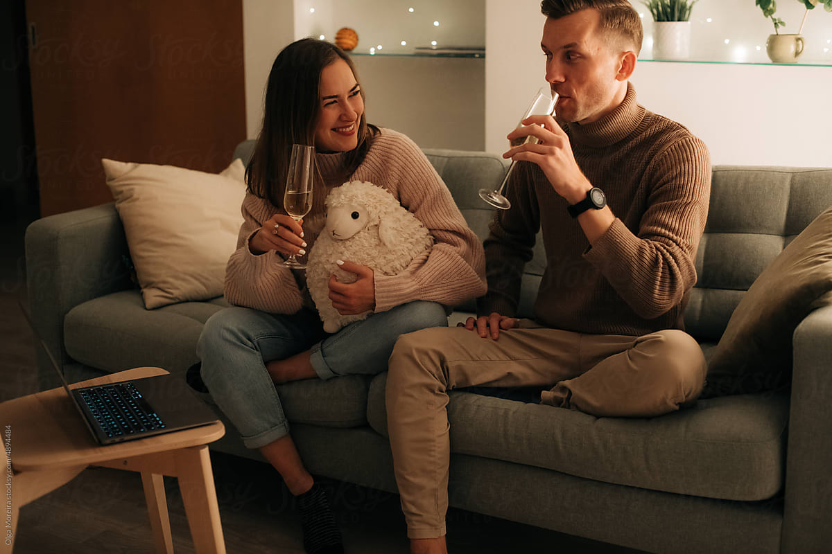 Couple smiling and drinking wine while having a video call