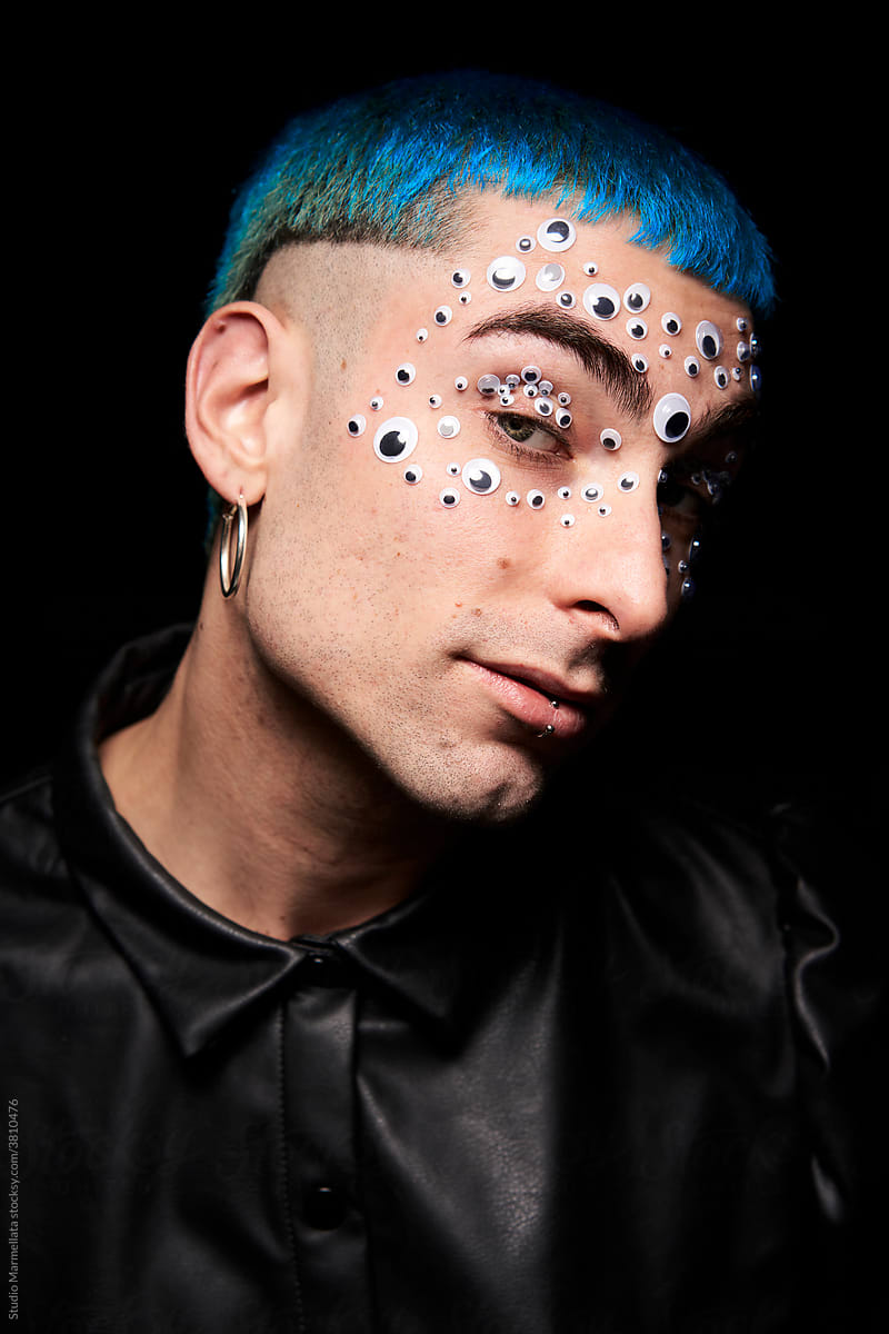 Content man with blue hair looking at camera in studio