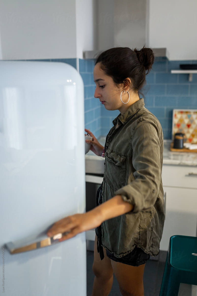 teen girl looking inside the fridge at home