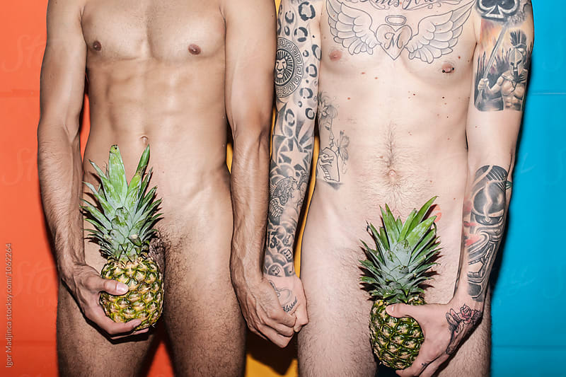 two naked young man hiding with pineapple private parts in front of the colorful background, food,party,youth, crazy, summer
