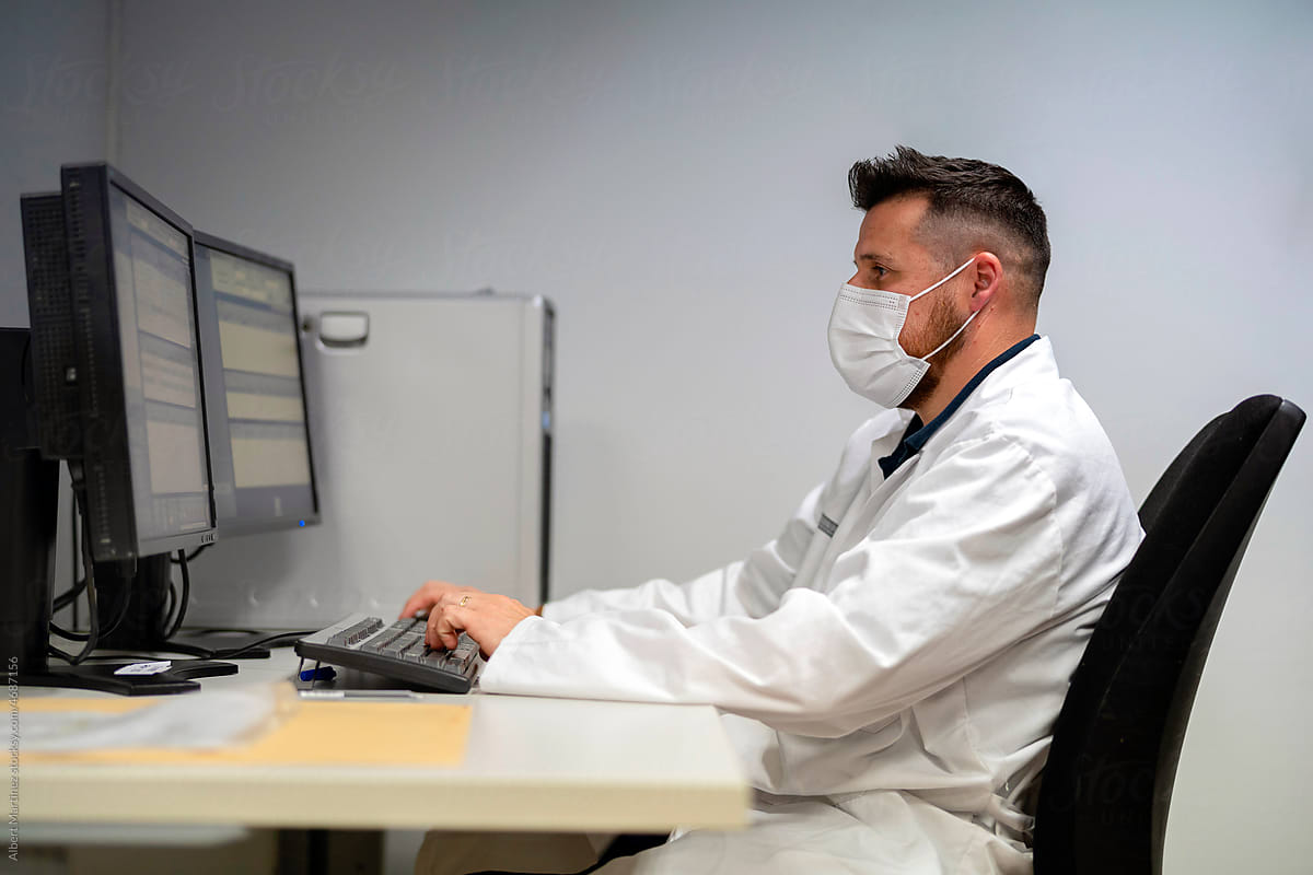 Male doctor entering data into computer