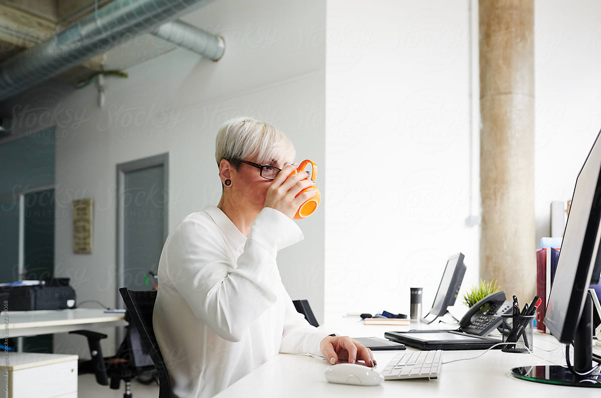 Contemporary businesswoman drinking coffee in office