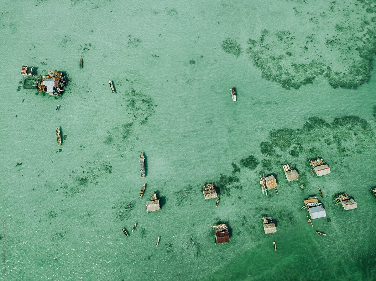 stilt houses and boats from sea nomads on an emerald reef from above, borneo