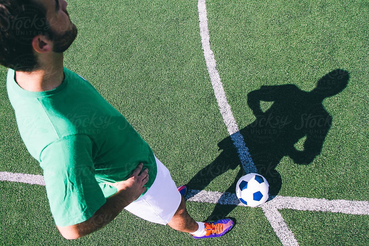 Soccer player with ball in a soccer field during a sunny day