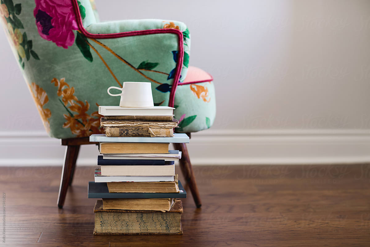 stack of books and coffee next to a chair