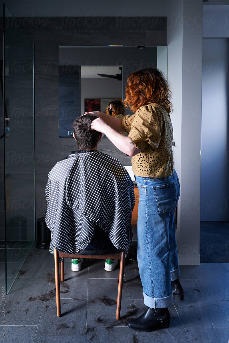 Woman having her haircut at home by visiting hairdresser during Pandemic