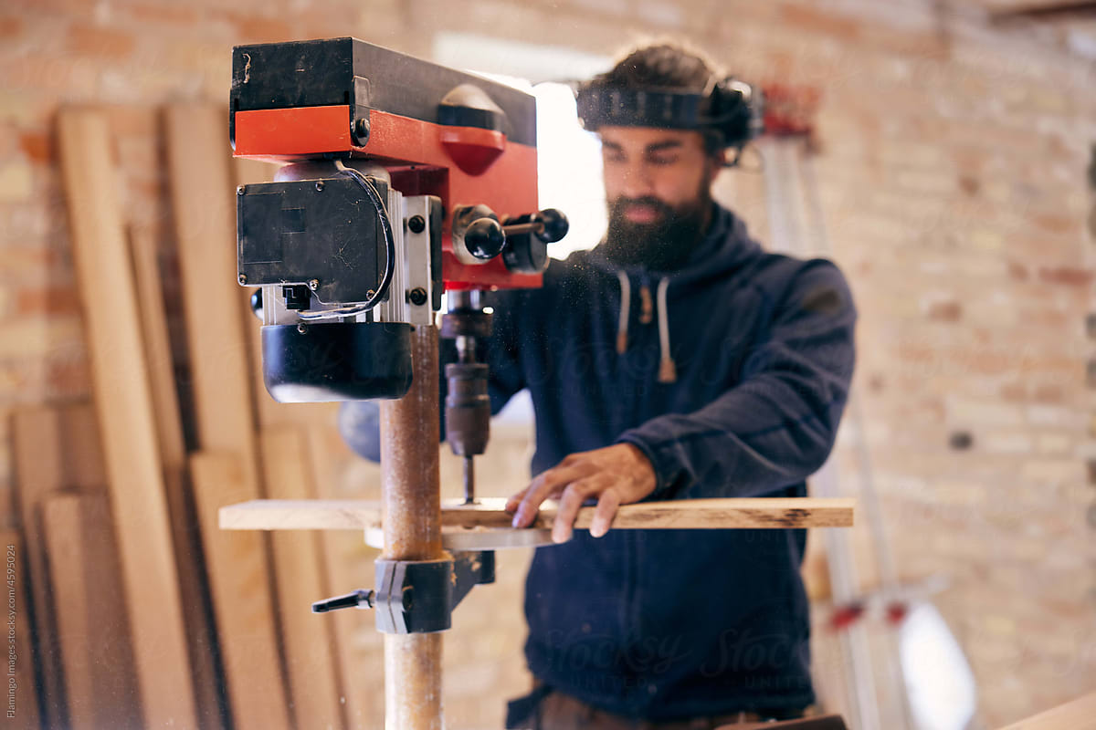 Woodworker using a drill press in his carpentry shop