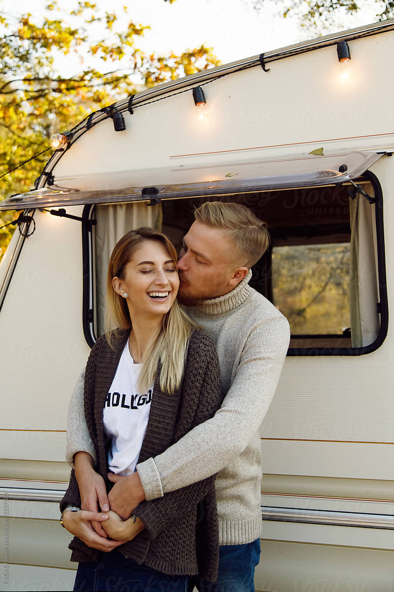 Young couple hugging and kissing near caravan