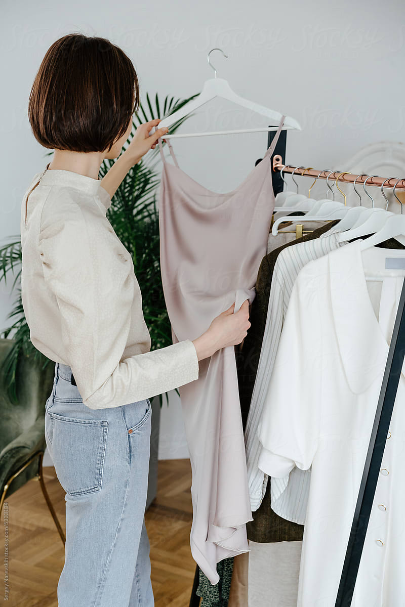 Female stylist choosing dress in showroom