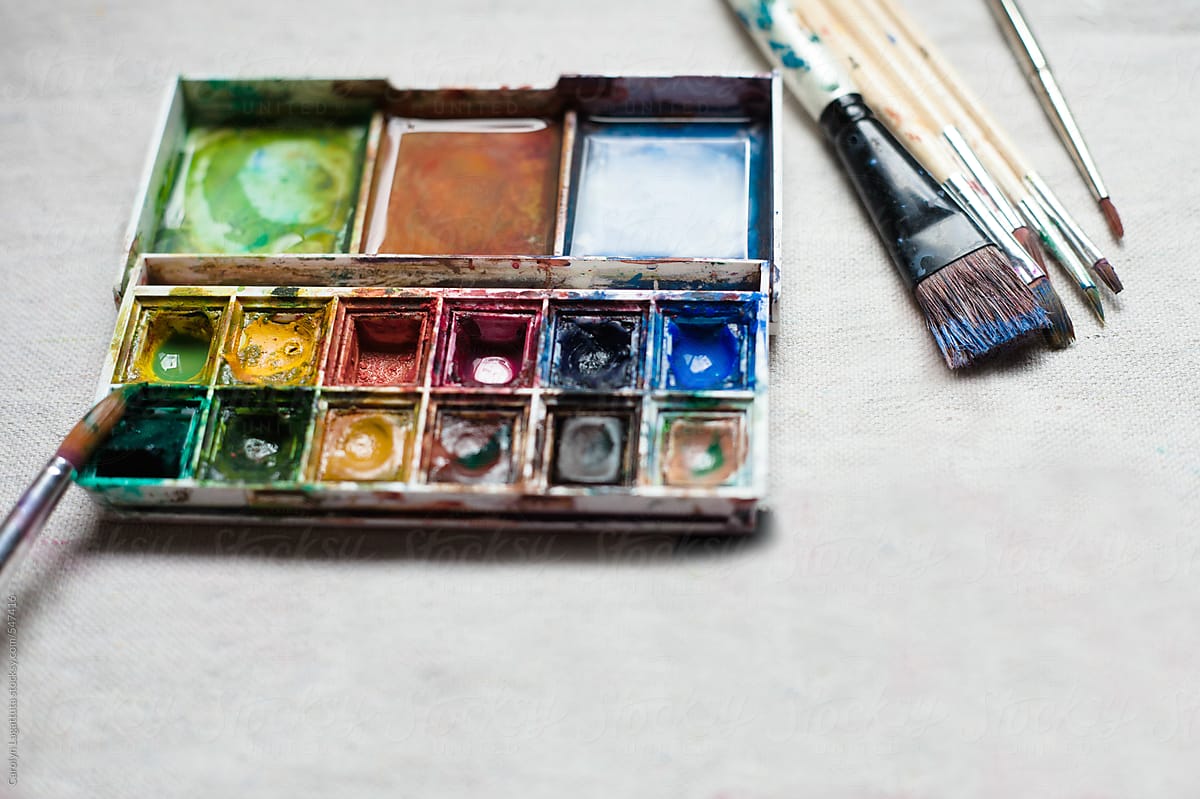 Mini palette of well loved paints on a canvas with brushes