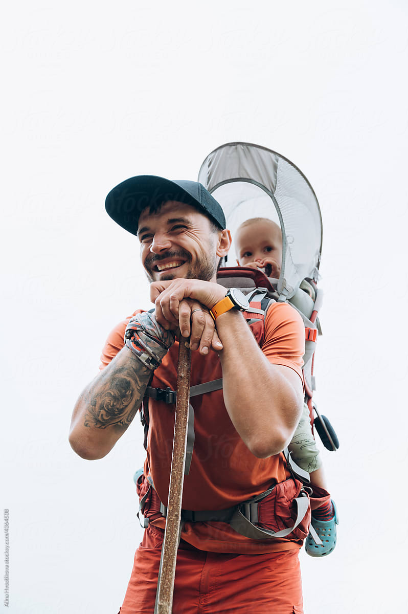 Happy dad with kid in backpack smiling during trekking