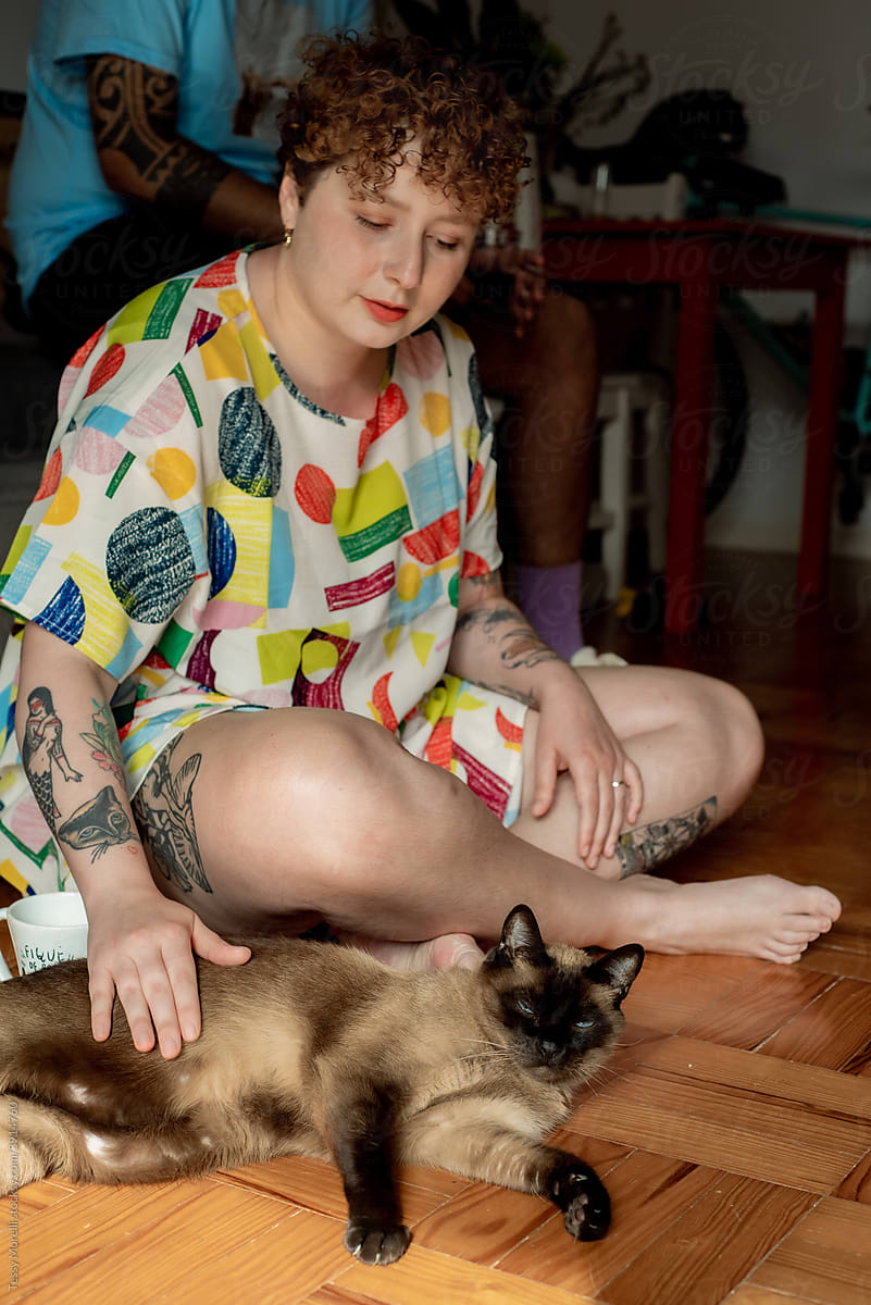 Woman on the floor cuddling her cat